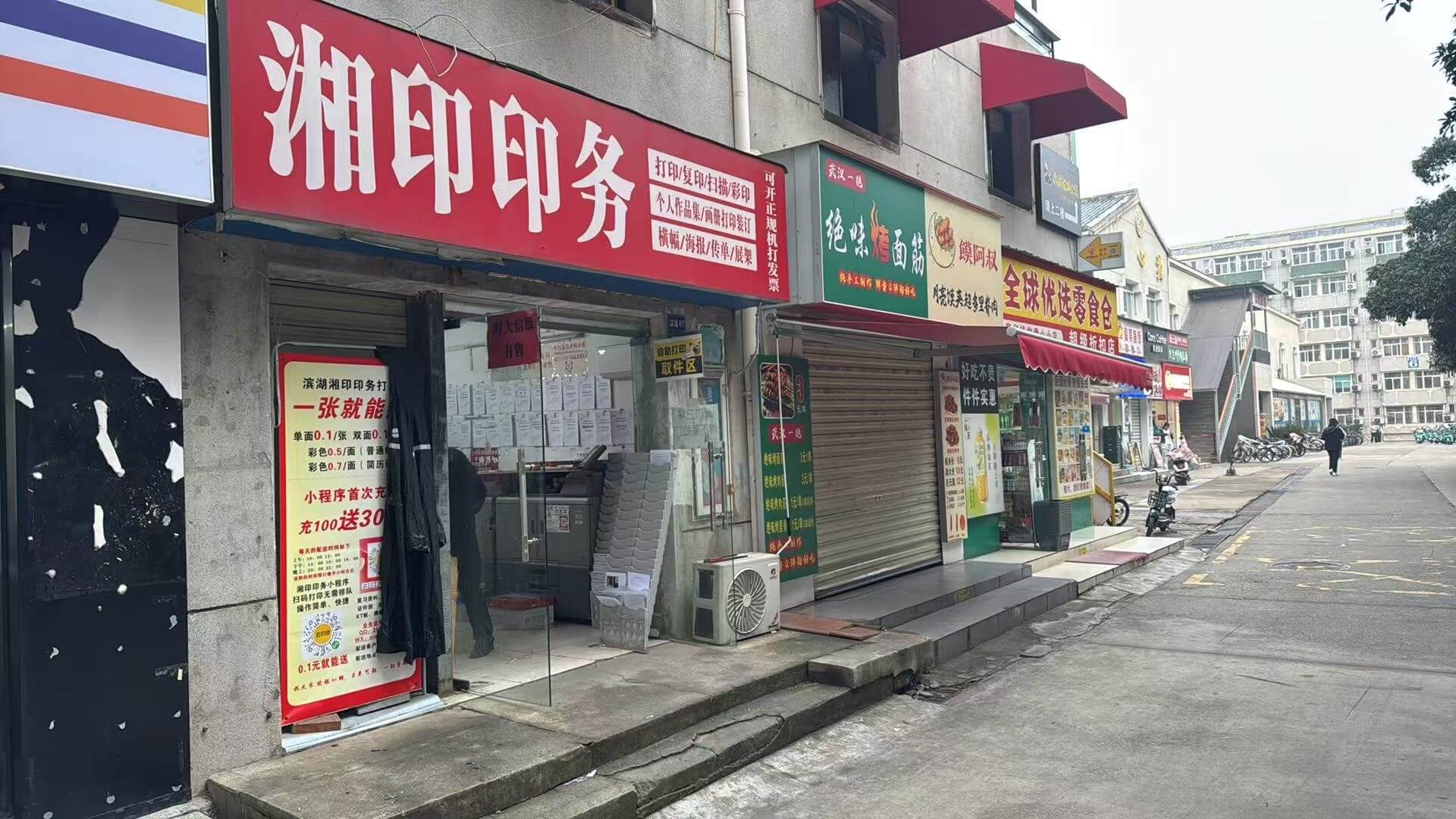 A print shop on a campus street with a self-service print pickup area.