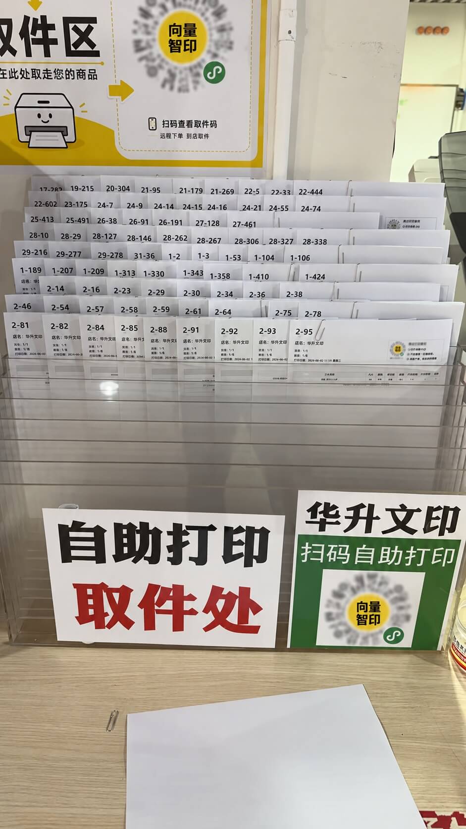 A print pickup station with numbered documents and signs for self-service printing.